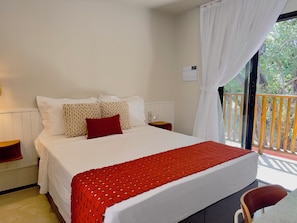 A hotel room with a bed, a nightstand, a red chair, and a view of the outdoors. - Liiv Nature Pipa (Tibau do Sul)
