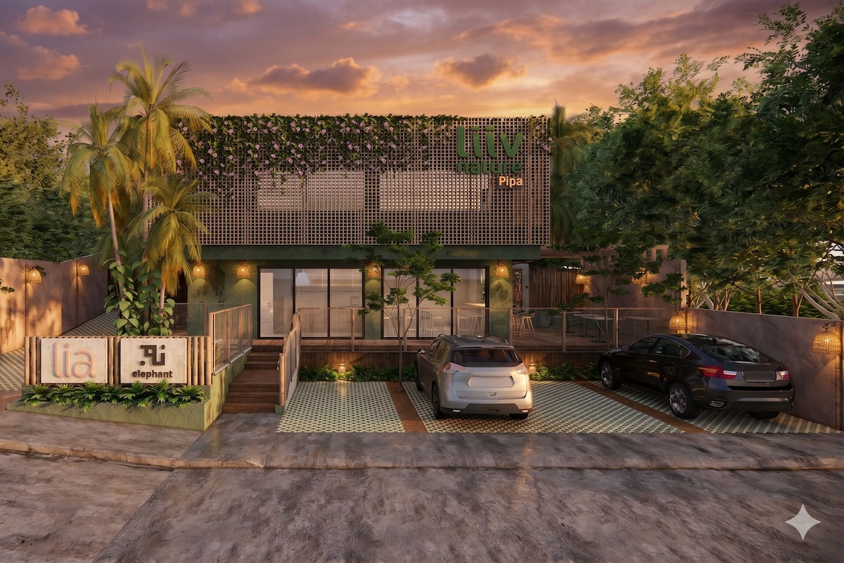 A modern building with a green facade, a covered entrance, and a car parked in front.
