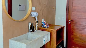 A bathroom with a granite sink, wooden vanity, a round mirror, and a wooden door.