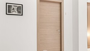 Una puerta de madera cerrada con un picaporte, una fotografía en blanco y negro enmarcada en la pared y un pequeño logotipo en la puerta.