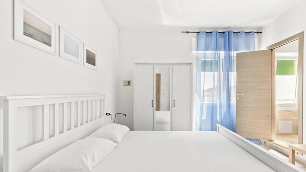 Un dormitorio con cama, armario, ventana con cortinas e imágenes enmarcadas en la pared.