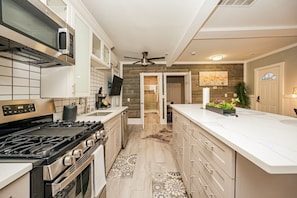 A modern kitchen with a stove, microwave, and a large island.