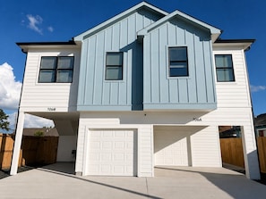 Ein zweistöckiges Haus mit Garage, überdachter Auffahrt und Holzzaun.