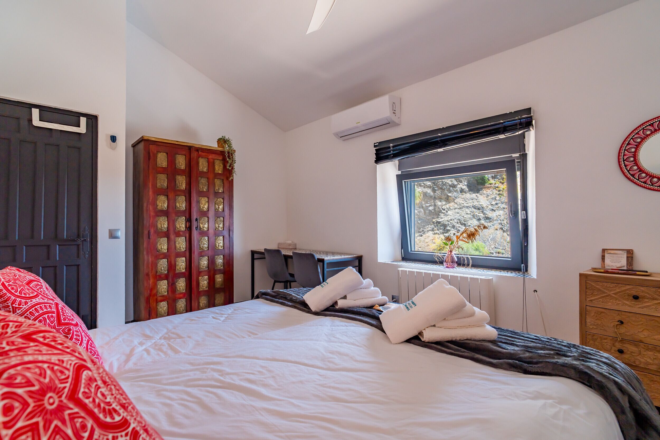 Una habitación de hotel con cama, escritorio, armario y ventana con vistas.