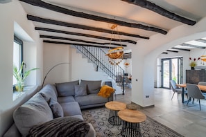 Ein modernes Wohnzimmer mit einem grauen Sofa, einem Holztisch und einer Treppe, die in eine andere Ebene führt.