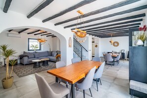 Ein modernes Wohnzimmer mit einem Holzesstisch, grauen Sofas und einer Treppe, die in einen oberen Bereich führt.