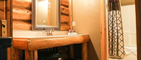 A wooden bathroom vanity with a mirror, sink, and a towel rack.