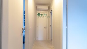 En hall med en dörr märkt med texten ”facile immobiliare”, en luftkonditioneringsanläggning som är monterad i taket och en ljusströmbrytare.