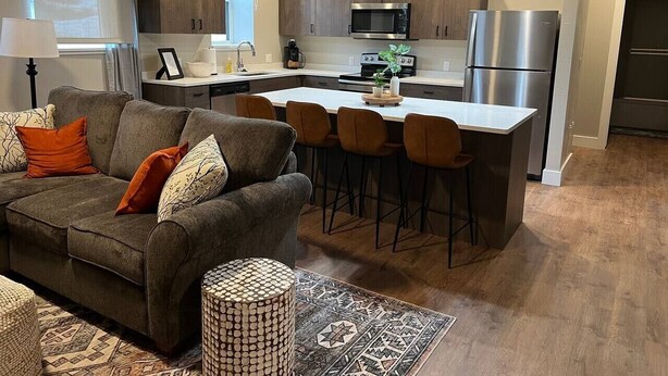 A modern kitchen with a central island, bar stools, and a dining area. - #101- Spacious 2-bedroom apartment in La Grande. (La Grande)