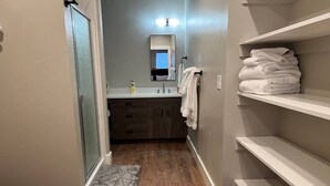A bathroom with a shower, a sink, a mirror, and a towel rack. - #101- Spacious 2-bedroom apartment in La Grande. (La Grande)