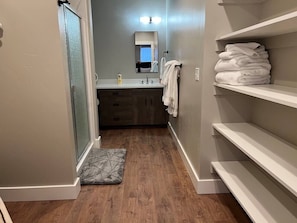 A bathroom with a shower, a sink, a mirror, and a towel rack.
