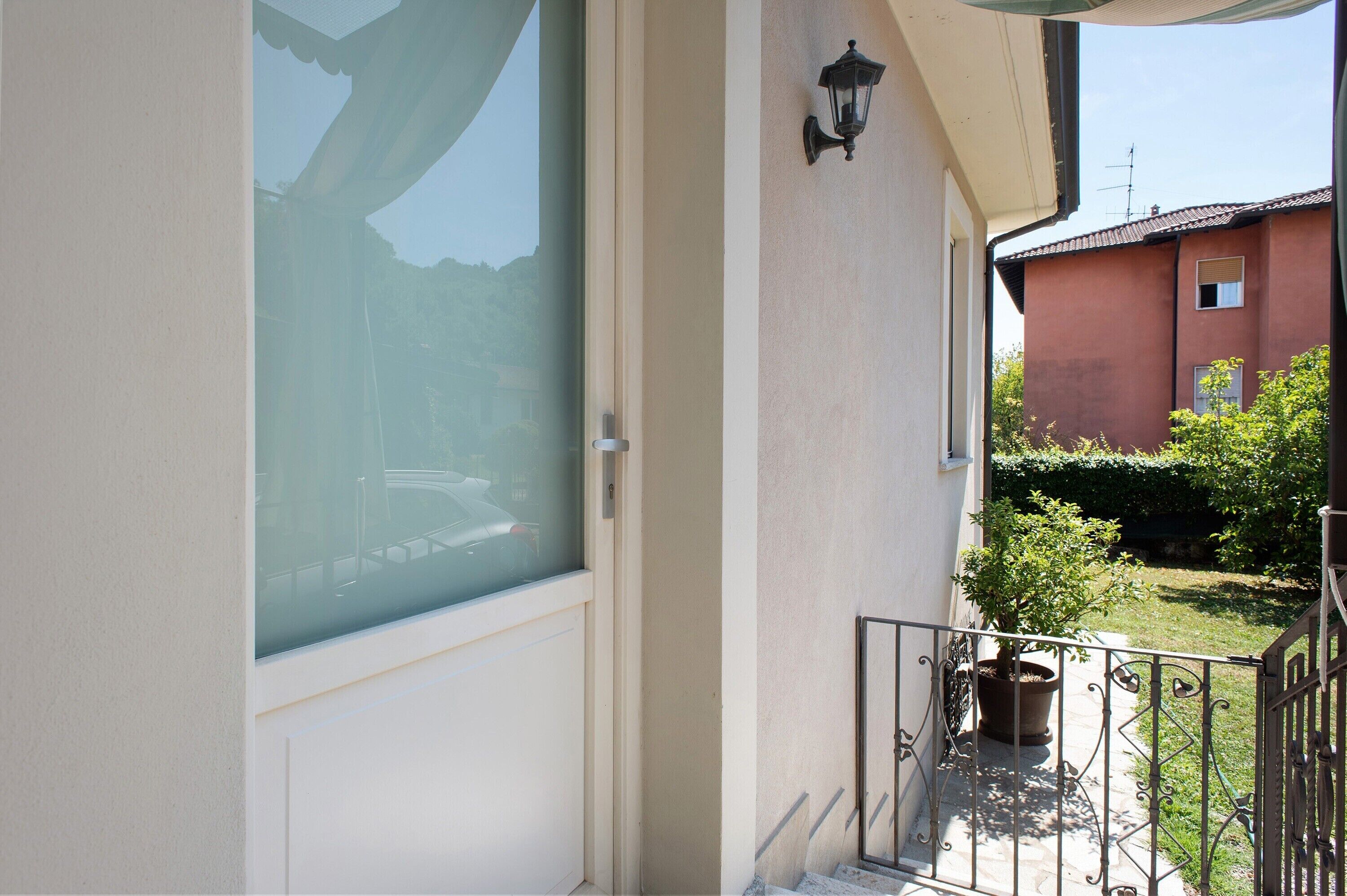 A balcony with a glass door, a potted plant, and a metal railing.