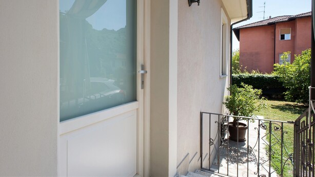 Un balcon avec une porte vitrée, un pot de fleurs et une rambarde en métal.