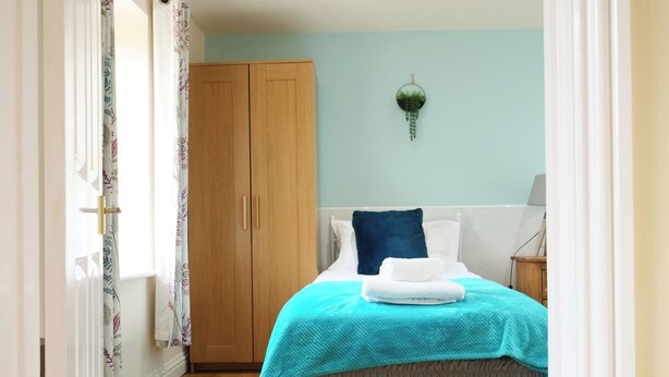 Une chambre à coucher avec un lit, une armoire et une plante suspendue.