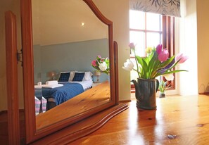 Ein Schlafzimmer mit Bett, Nachttisch und einem Spiegel, der den Raum widerspiegelt.