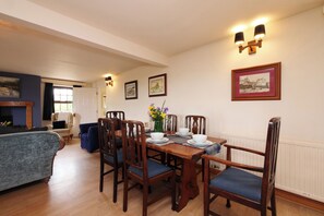 A dining area with a wooden table, chairs, and wall-mounted light fixtures. - Albany @ Summerfield Farm (Whitby)