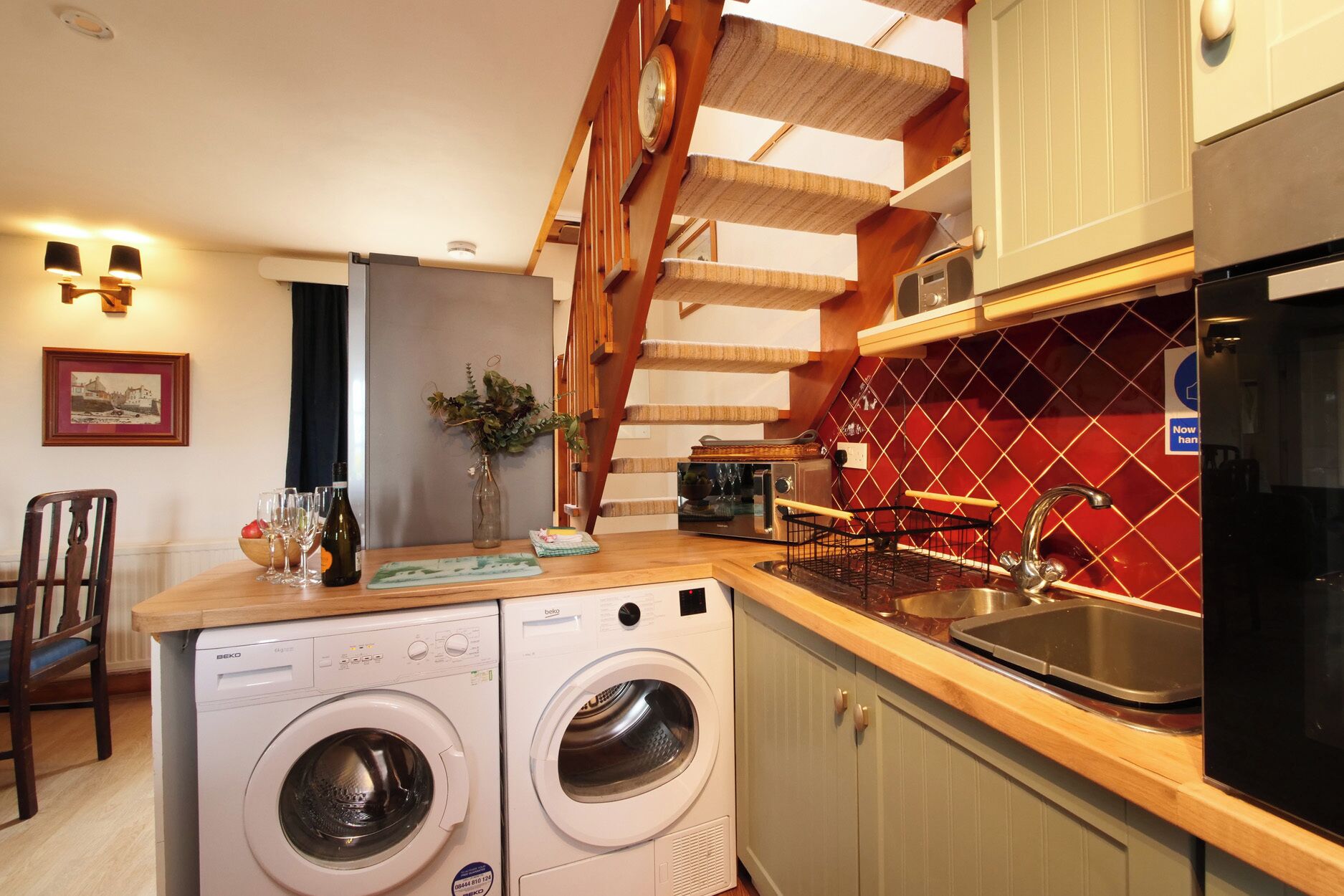 A compact kitchen with a washing machine, a toaster, and a sink.