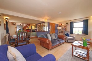 A living room with a sofa, armchairs, a coffee table, and a dining area with chairs and a table. - Albany @ Summerfield Farm (Whitby)