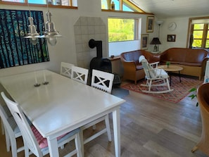 Ein gemütliches Wohnzimmer mit einem weißen Tisch, einem braunen Ledersofa, einem Schaukelstuhl und einem Kamin.