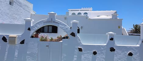 A white building with a sign reading 'Calle El Morro' and a gated entrance.