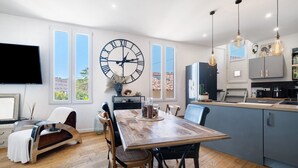 Eine moderne Küche mit Essbereich, einer großen Wanduhr und einem Fernseher.