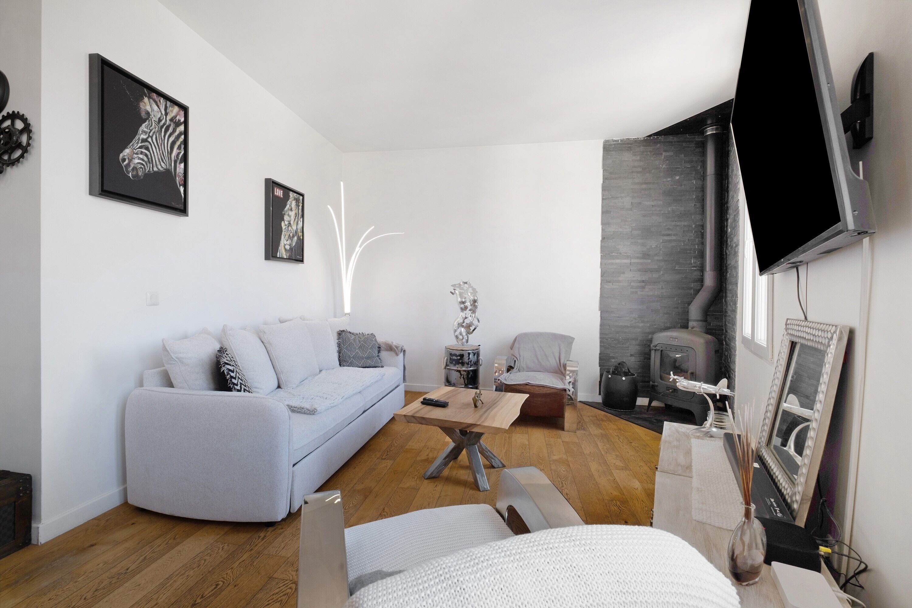 Ein modernes Wohnzimmer mit einer Couch, einem Couchtisch, einem Sessel, einem Kamin und einem an der Wand befestigten Flachbildfernseher.