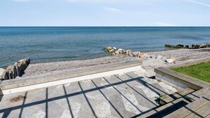 Une vue sur la côte, avec une terrasse en bois, un sentier en pierre et une rive rocheuse.