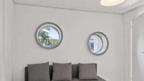 Une pièce moderne avec un canapé gris, deux miroirs ronds et un plafond blanc.