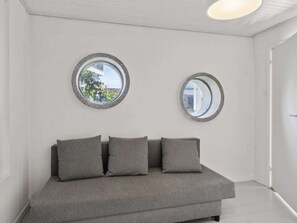 Ein modernes Zimmer mit einem grauen Sofa, zwei runden Spiegeln und einer weißen Decke.
