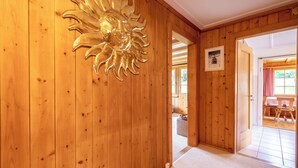 Ein Holzboden-Flur mit Wanddekoration in Sonnenform, einem gerahmten Bild und Blick in einen Essbereich.
