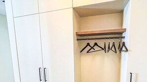 Un dressing avec une étagère en bois, une tringle pour suspendre les vêtements et un porte-chaussures.