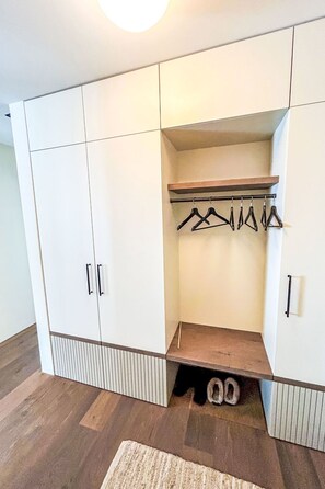 Ein begehbarer Kleiderschrank mit Holzregal, Ablage für Kleidung und Schuhablage.