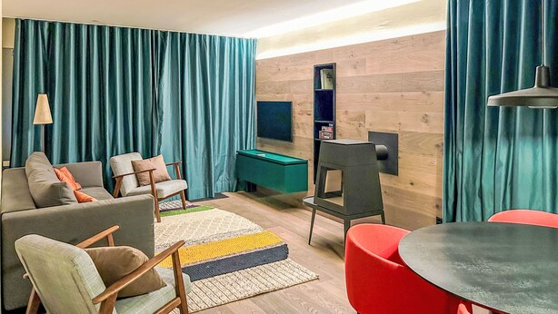 Un salon moderne comprenant un canapé, des fauteuils, une table de billard et un téléviseur.