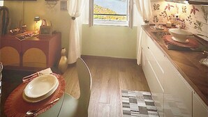 Eine kompakte Küche mit Seeblick, ein Essbereich mit gedecktem Tisch und eine kleine Kochinsel mit Lampe.