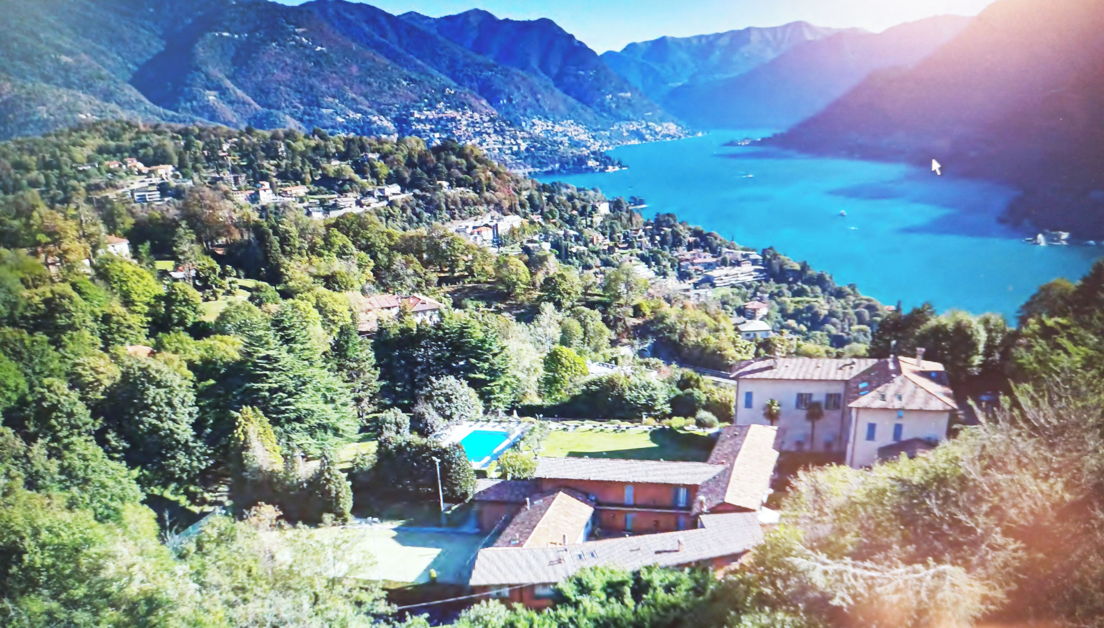 A mountainous landscape with a body of water, houses, and a swimming pool.