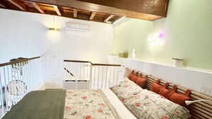 Ein Schlafzimmer mit Bett, Nachttisch, Holz-Kopfteil, einer Treppe und einer Wandleuchte.