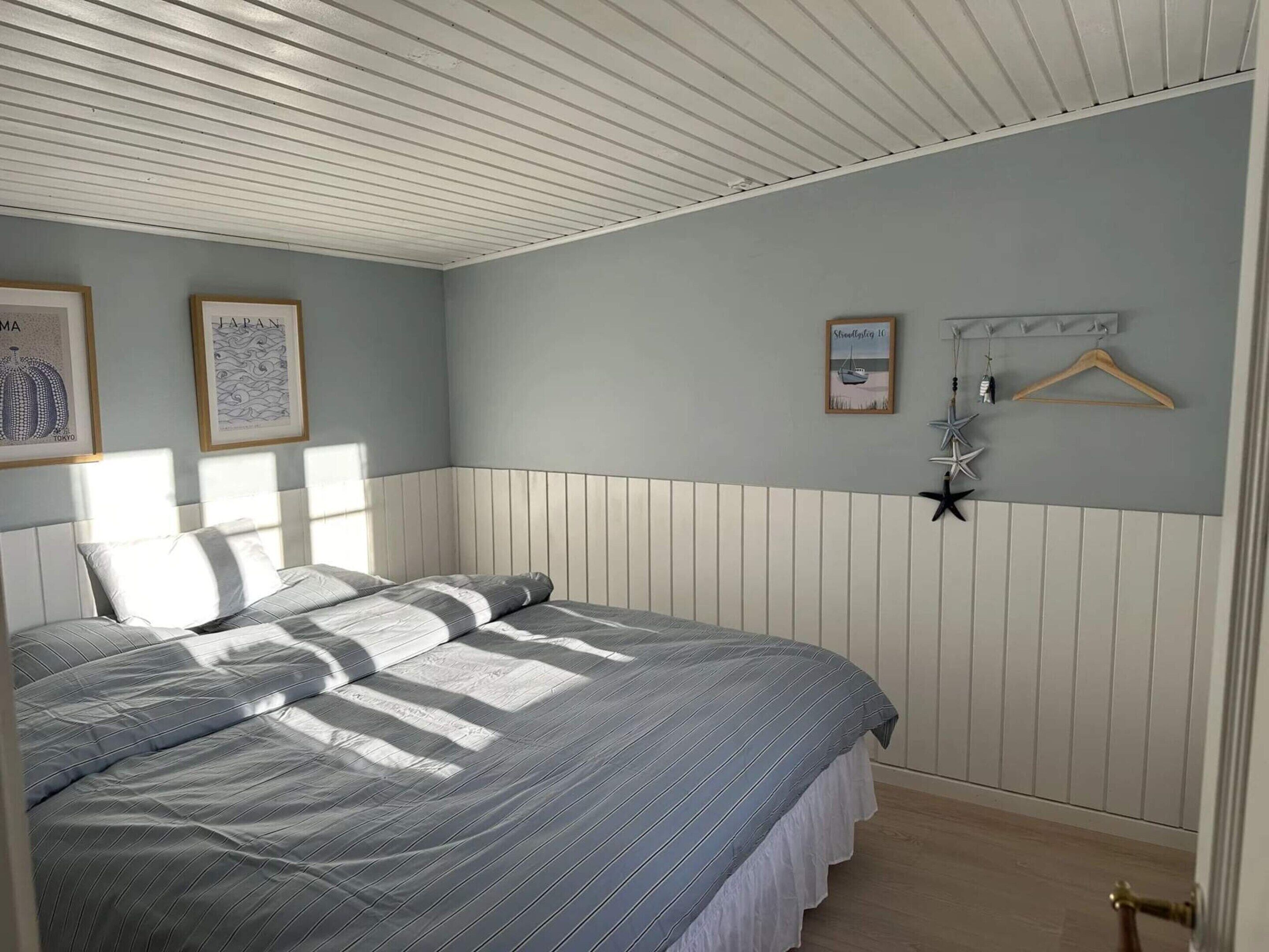 Une chambre à coucher avec un lit, un porte-manteau fixé au mur et des tableaux encadrés.