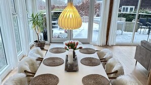 A dining table set with placemats, candles, and a vase of flowers. - 4 Star Holiday Home in Jaegerspris (Jægerspris)