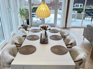A dining table set with placemats, candles, and a vase of flowers. - 4 Star Holiday Home in Jaegerspris (Jægerspris)