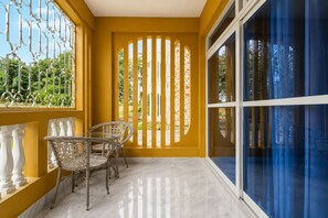 Ein Balkon mit gelber Wand, Glastür und weißer Brüstung.
