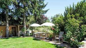 A backyard with a lawn, a wooden fence, a table with chairs, and potted plants. - Apartment Jessy by Interhome (Gau-Algesheim)
