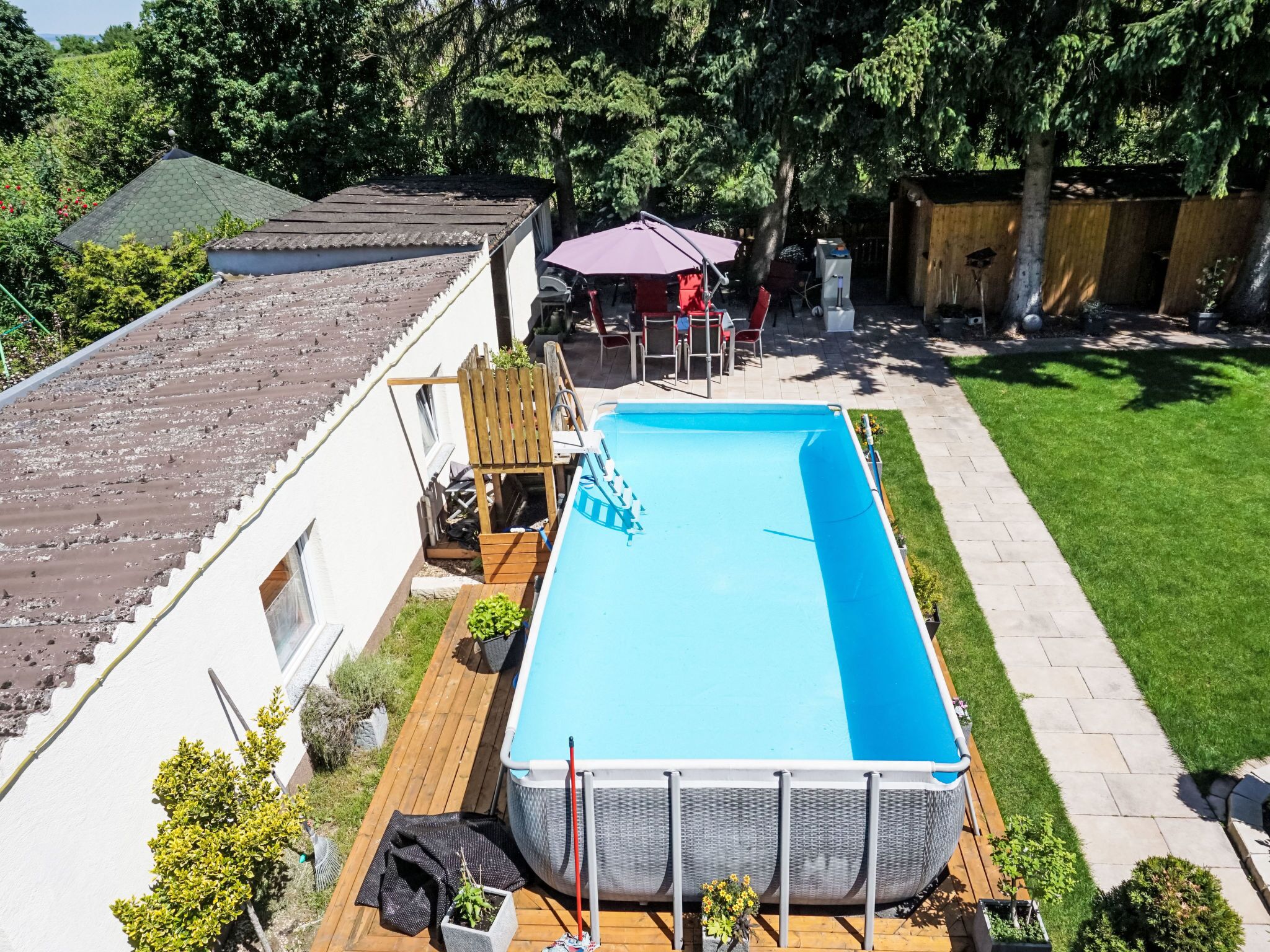 Ein rechteckiger Pool mit Holzterrasse, umgeben von einem gepflegten Rasen und einem Holzzaun.