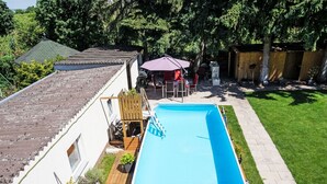 A rectangular swimming pool with a wooden deck, surrounded by a well-maintained lawn and a wooden fence. - Apartment Jessy by Interhome (Gau-Algesheim)