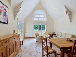 Ein geräumiges Loft mit hoher Decke, großen Fenstern, einem Holzespeisetisch und einer gemütlichen Sitzecke.
