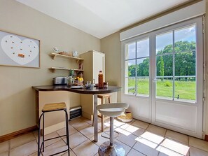 Eine Küche mit großem Fenster, einem Barhocker, einer Spüle und einem Kühlschrank.