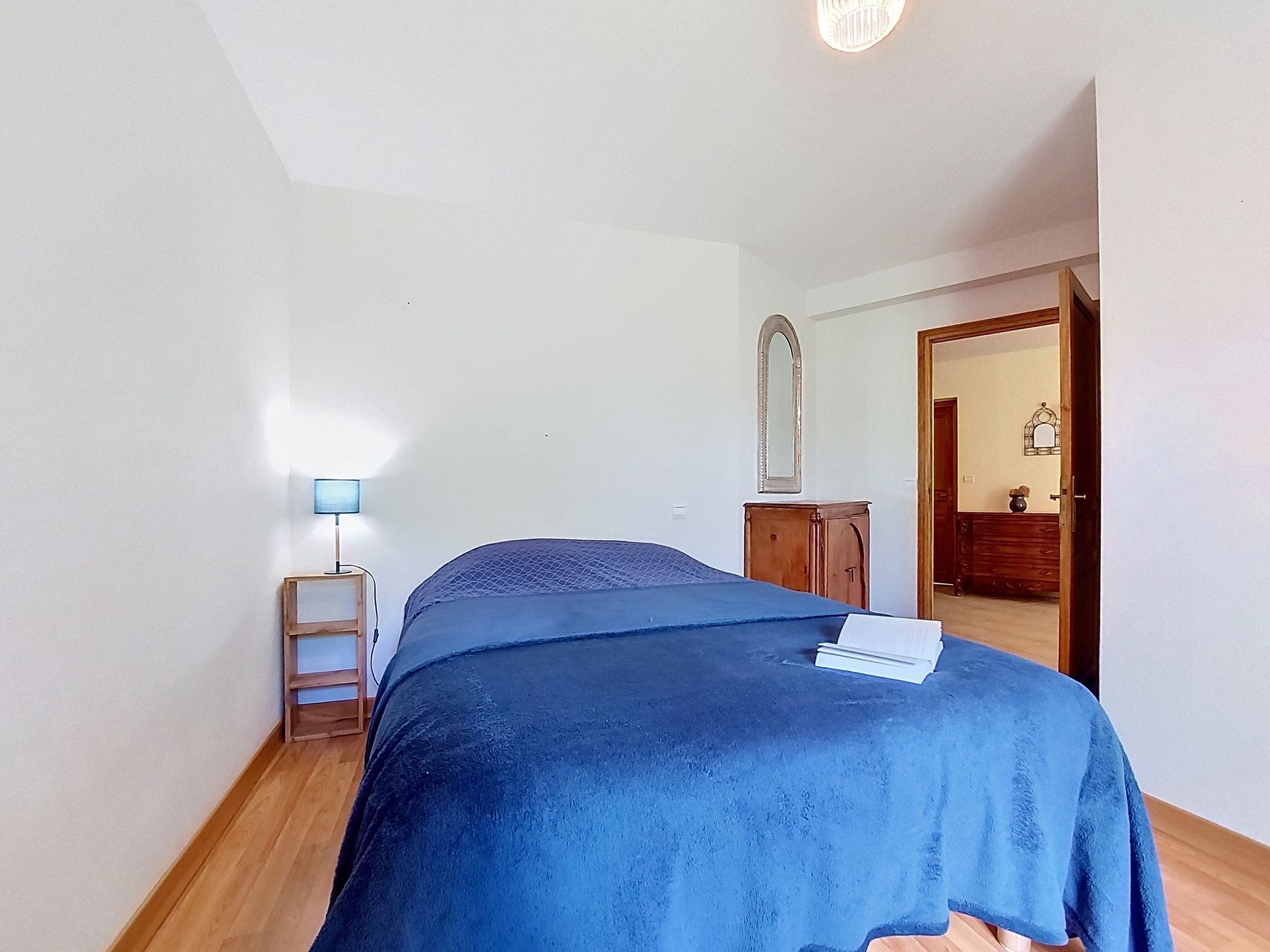 Ein Schlafzimmer mit einem Bett, einem Nachttisch, einer Lampe, einem Kleiderschrank und einem Spiegel.