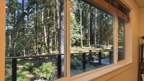 Ein Zimmer mit großem Fenster und Blick auf eine bewaldete Landschaft.