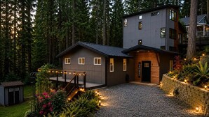 Ein modernes, zweistöckiges Haus mit Schotterauffahrt, umgeben von einem Wald.