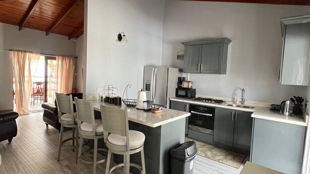 Een moderne keuken met een eethoek, houten plafond en uitzicht op de omgeving.