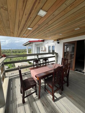 Eine Holzterrasse mit Tisch und Stühlen mit Blick auf ein Haus und Grünflächen.